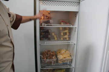Cook shows how food is stored on the shelves of the refrigerator in the restaurant’s kitchen. 
