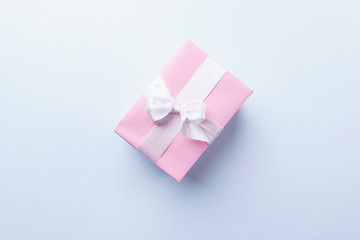 Present box in wrapping paper and tied with satin ribbon on blue background, copy space. Women day, birthday, Valentine' s day gift