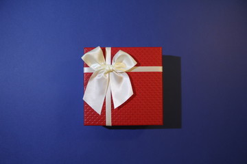 beautiful red christmas present with white bow on blue background