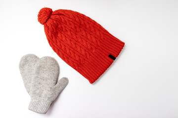 Orange knitted hat and warm winter mittens on white background