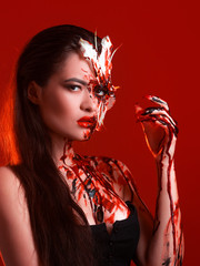 Blood Lily, scary and sexy Halloween look. Beautiful young brunette girl on red background.