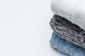 Stack of cozy comfortable homely clean washed knitted pullovers in pastel colors, laundry and washing clothes concept. White background, copy space.