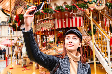 Young woman taking selfies on christmas market