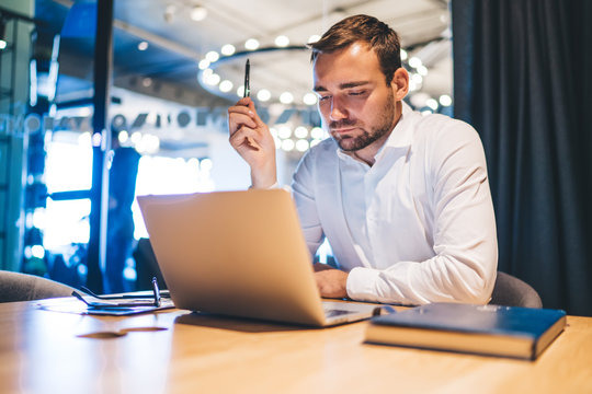 Young male proud ceo working online with laptop application checking information on website, handsome Caucasian trader with spectacles in hand browsing internet via modern netbook connected to 4g