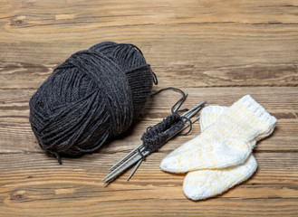 Knitted baby socks next to a ball of thread