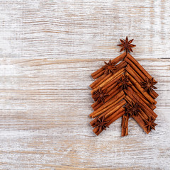 Christmas card with fir tree made from spices cinnamon sticks, anise star on rustic wooden background. Celebration concept. Place for text, Flat lay, top view, copy space