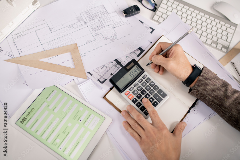 Poster View of hands of engineer with pen and calculator making notes in notebook