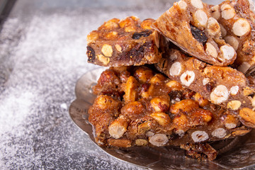 Italian sweet nuts, hazelnuts, almonds, figs, honey dessert over on sugar powder surfase