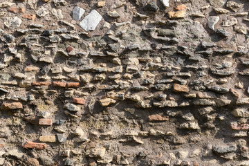 A fragment of the original masonry of raw stones built by ancient Rome. Background. Pattern. Ocher, brown.