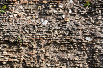 A fragment of the original masonry of raw stones built by ancient Rome. Background. Pattern. Ocher, brown.