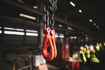 Shallow depth of field (selective focus) image with red industrial crane lifting hooks inside a...