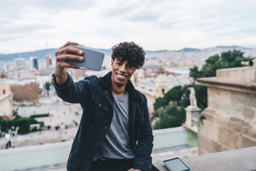 Cheerful man taking selfie against cityscape