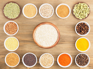 Rice, buckwheat, oat, millet, green cardamom, allspice, dry ginger, pepper chili, fenugreek, turmeric, cloves, masala, mustard seeds on brown wooden background