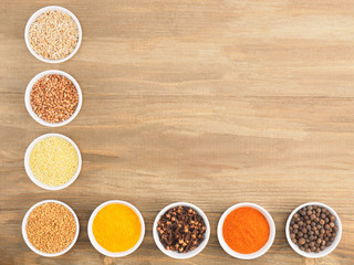 Allspice, pepper chili, fenugreek, cloves, turmeric, millet, oat, buckwheat on brown wood background. Indian cuisine, ayurveda, naturopathy concept