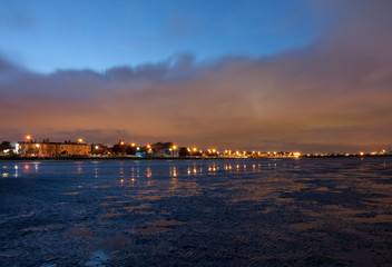 Twilight with starburst effects from street lights. Low tide along Sandymount Strand beach, Dublin, Ireland. Urban view during evening nightfall