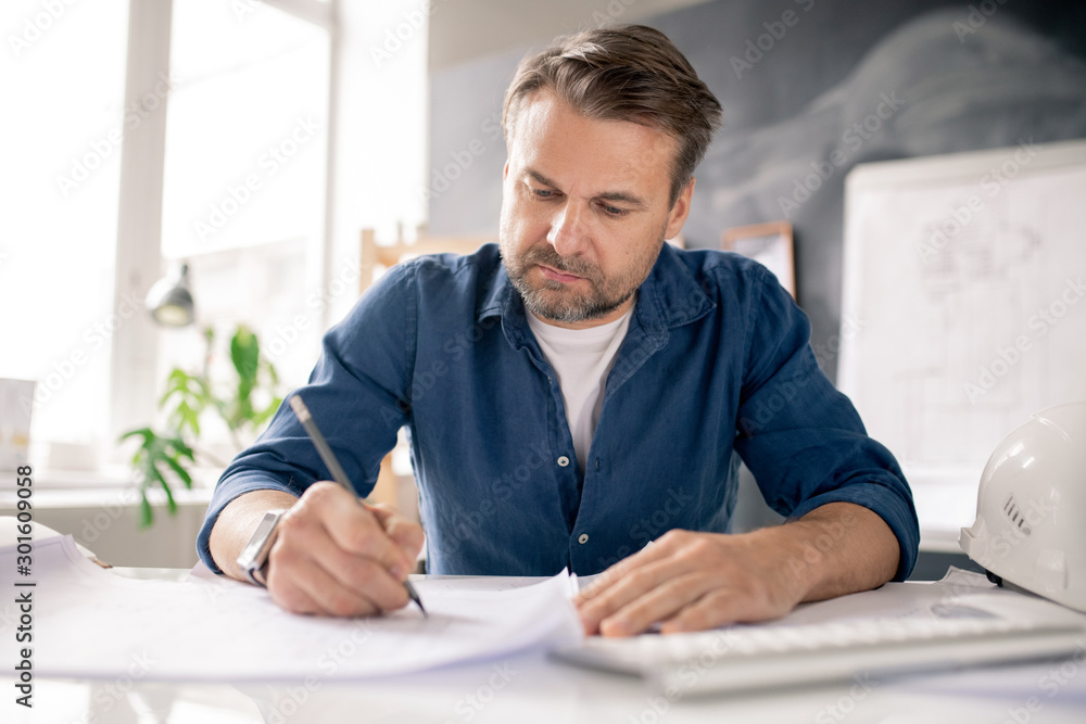 Poster serious architect with pencil drawing new sketch on paper while bending by desk