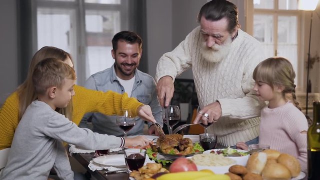 Respected senior grandfather carving traditional roast turkey during celebration Thanksgiving day