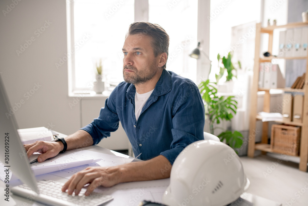 Poster Serious engineer concentrating on work while sitting in front of computer screen