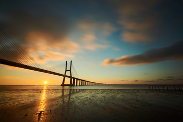 Fototapeta na wymiar Sun rising under the Vasco da Gama bridge in Lisbon, Portugal