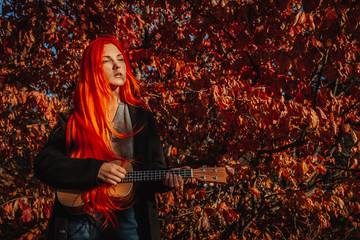 Sexy redhead girl with long hair plays the ukulele. Perfect woman portrait. Gorgeous strong and...