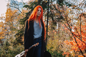 Sexy redhead girl with long hair plays the ukulele. Perfect woman portrait. Gorgeous strong and...