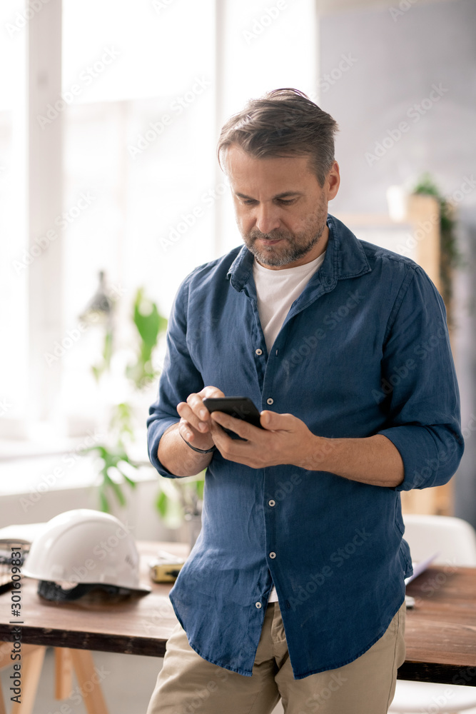 Poster contemporary mobile engineer with smartphone scrolling through contacts