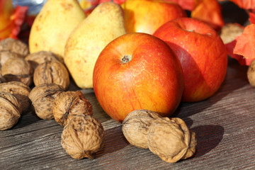 Äpfel, Birnen und Walnüsse auf einem rustikalen Holztisch als herbstliches Motiv
