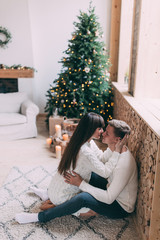 Photo shoot in the studio of a young married couple. Photographing of pregnancy. A guy with a girl is celebrating Christmas. New Year's love story.