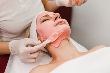 Doctor beautician applies anti-aging mask to woman face. Girls lies on a cosmetology procedure. Facial mask close-up