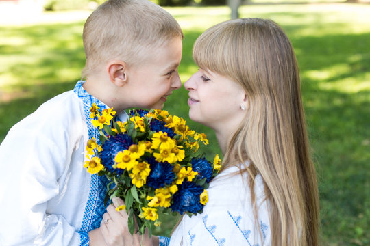 mother and son in embroidered shirts. national clothes of Ukraine. a boy gives flowers to his mother