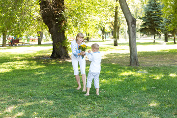 Fototapeta premium mother and son in embroidered shirts. national clothes of Ukraine. a boy gives flowers to his mother
