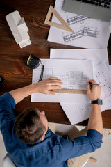 Overview of mature professional engineer working over new sketches by table © pressmaster