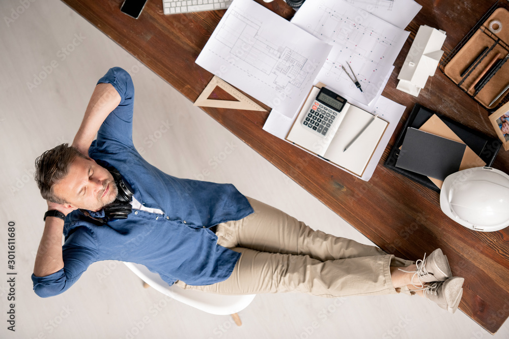 Aufkleber top view of relaxed engineer in casualwear enjoying break by workplace