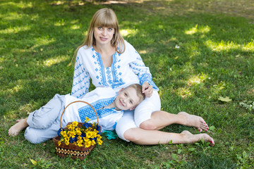 mother and son in embroidered shirts. national clothes of Ukraine. mother and son sitting on the grass