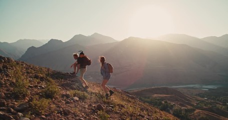 Caucasian couple hiking together with backpacks, helping each other on their way up the mountains - freedom, active lifestyle concept 4k footage - Powered by Adobe