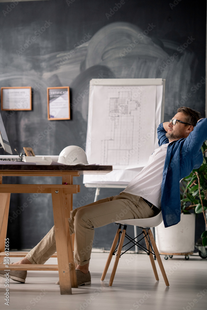 Aufkleber relaxed engineer sitting on chair by table and watching video on computer screen