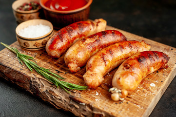 Grilled sausages with spices, ketchup and rosemary on a stone table, ready to eat