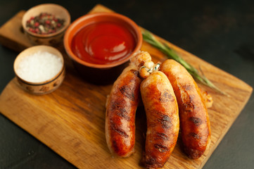 Grilled sausages with spices, ketchup and rosemary on a stone table, ready to eat