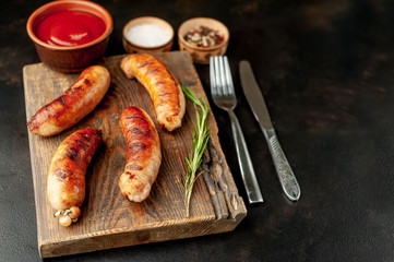 Grilled sausages with spices, ketchup and rosemary on a stone table, ready to eat