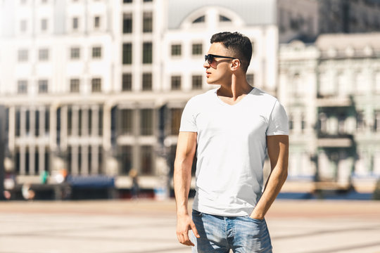 Outdoors Leisure. Stylish guy in sunglasses standing on the street hand in pocket looking aside pensive