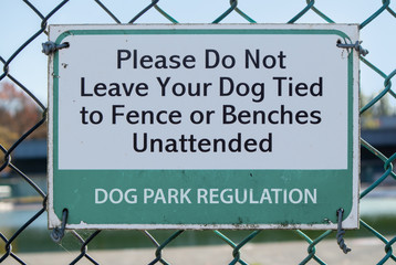 Dog park regulation sign. Please do not leave your dog tied to fence or benches unattended. 