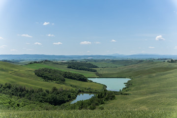 Fototapeta na wymiar landscape with, ponds, green fields and blue sky in Tuscany, Italy