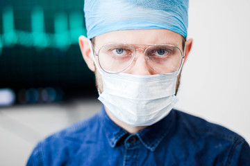 young male surgeon doctor with glasses in uniform in the operating room.