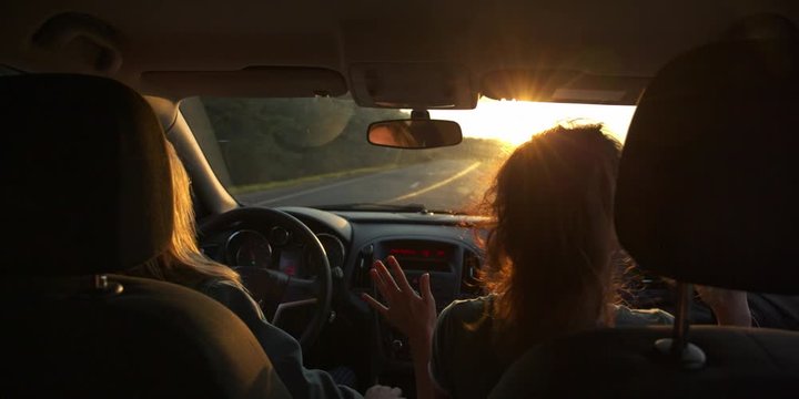 Fun multinational Young Women Dance and laugh in Moving Car. Slow Motion. Sunset on background. flares