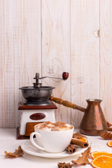Cup of coffee with marshmallows and cocoa, leaves, dried oranges, spices, on a white background. Delicious hot autumn drink, morning mood. Copy space.