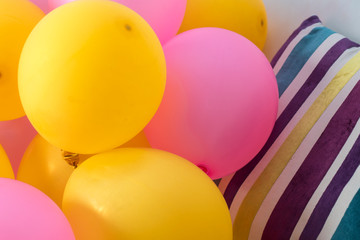 Pink and yellow balloons and colorful pillow