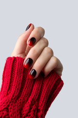 Female hand with red black ombre gradient nails in sweater © Darya Lavinskaya
