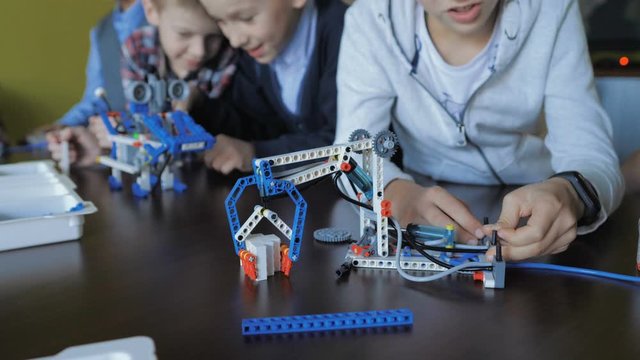 Children in the classroom make figures with teacher. Modern technology concept