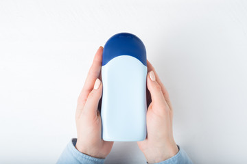 Blue bottle for cosmetic product in a female hands. White background