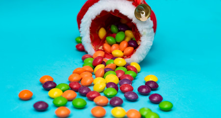 Multi-colored colored small sweets scattered from a Christmas boot. Candy boom. Blue background